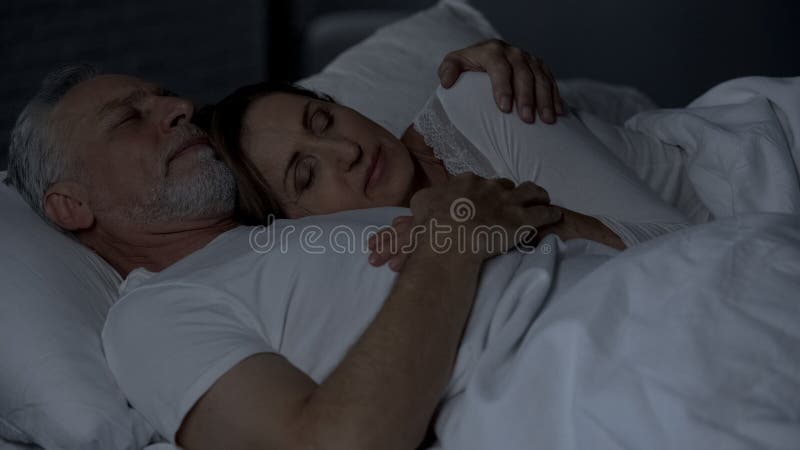Femme supérieure se trouvant sur le coffre masculin, couple dormant dans le lit, homme l'étreignant image stock Femme supérieure se trouvant sur le coffre masculin, couple dormant dans le lit, homme l'étreignant image stock