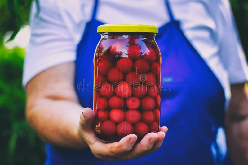 Femme supérieure tenant un pot de compote de cerise photos stock Femme supérieure tenant un pot de compote de cerise photos stock