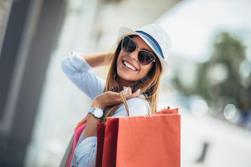 Femme tenant des sacs à provisions et souriant - dehors images stock Femme tenant des sacs à provisions et souriant - dehors images stock
