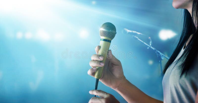 Woman holding microphone and singing on concert stage background. Woman holding microphone and singing on concert stage background.