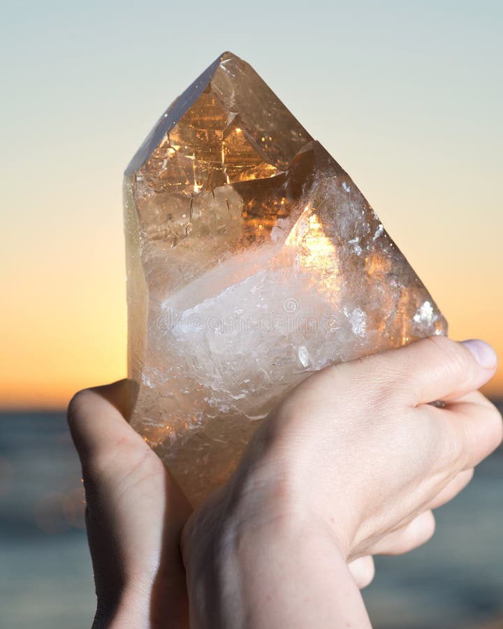 Femme tenant le quartz citrin naturel énorme de cathédrale du Brésil dans sa main au lever de soleil photo libre de droits Femme tenant le quartz citrin naturel énorme de cathédrale du Brésil dans sa main au lever de soleil photo libre de droits
