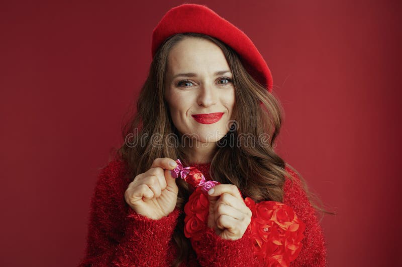 Femme tendance souriante en chandail rouge et béret avec bonbons photos libres de droits