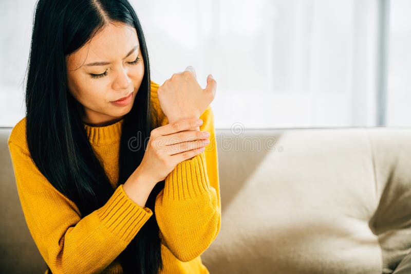 Depicting wrist pain, Woman holds her achy hand suggesting Carpal Tunnel Syndrome or discomfort. Illustrating inflammation symptoms and hand discomfort. Health care concept. Depicting wrist pain, Woman holds her achy hand suggesting Carpal Tunnel Syndrome or discomfort. Illustrating inflammation symptoms and hand discomfort. Health care concept