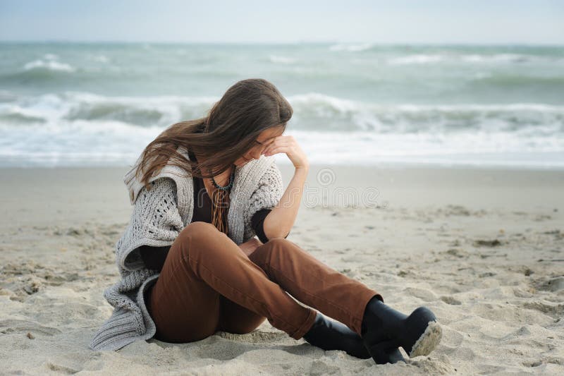 Femme triste s'asseyant sur une plage de mer photos stock Femme triste s'asseyant sur une plage de mer photos stock
