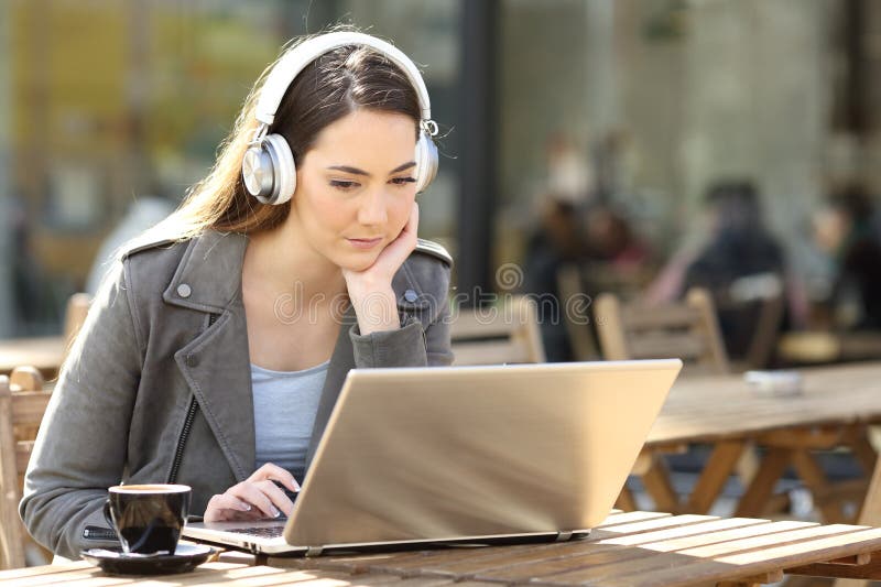 Femme utilisant un ordinateur portable et un casque dans la terrasse du bar image libre de droits