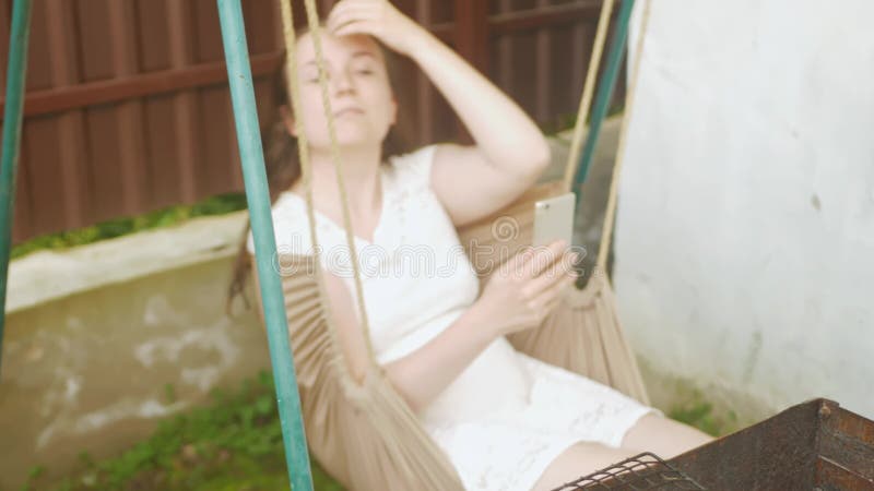 Femme utilise un smartphone. repos extérieur dans la cour de la maison. communiquer avec des amis dans la nature l'internet clips vidéos