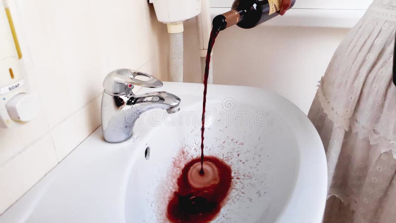 Femme versant du vin de la bouteille dans l'évier banque de vidéos