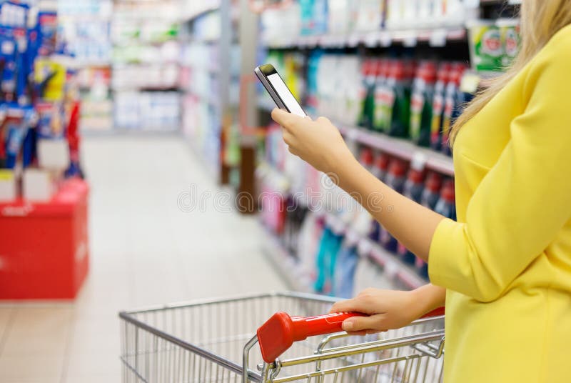 Femme vérifiant la liste d'achats sur son smartphone photo stock Femme vérifiant la liste d'achats sur son smartphone photo stock