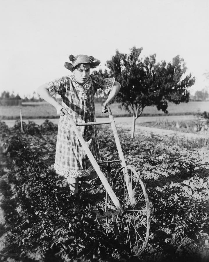 Femme à l'aide de la charrue de marche dans le jardin (toutes les personnes représentées ne sont pas plus long vivantes et aucun image libre de droits Femme à l'aide de la charrue de marche dans le jardin (toutes les personnes représentées ne sont pas plus long vivantes et aucun image libre de droits