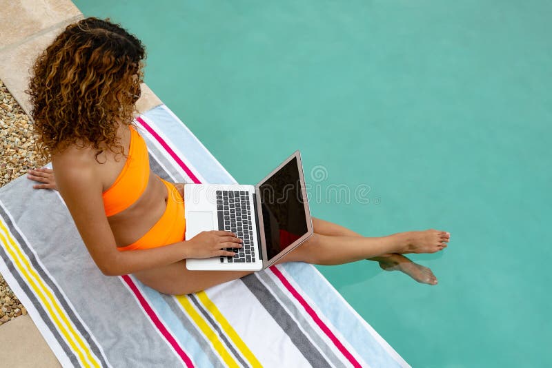 Femme à l'aide de l'ordinateur portable tout en se reposant au bord de la piscine photo libre de droits Femme à l'aide de l'ordinateur portable tout en se reposant au bord de la piscine photo libre de droits