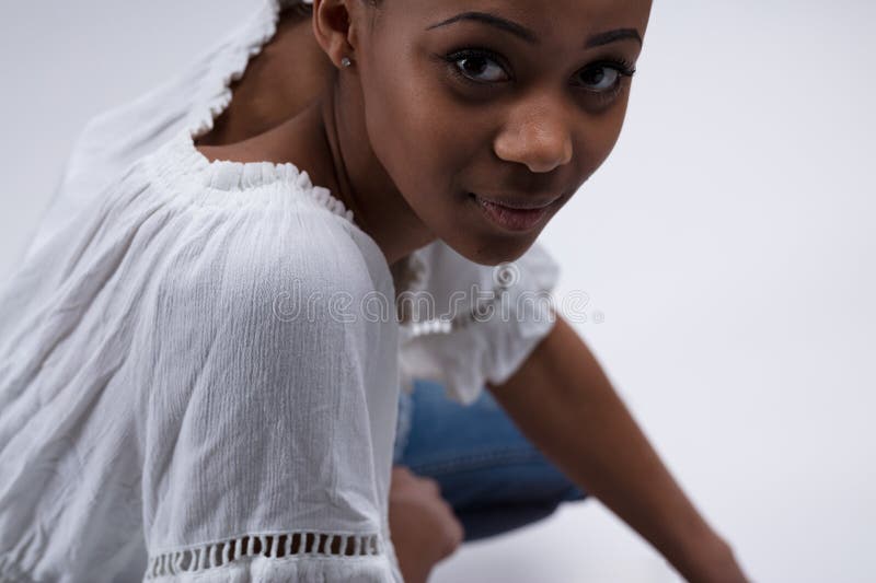 Femme à l'écoute portrait basse. Portrait d'en dessous d'une jeune femme assise en train d'écouter. portant une blouse blanche et un jean elle semble curieuse si vous êtes intéressant ou ennuyeux. elle est noire et très jolie