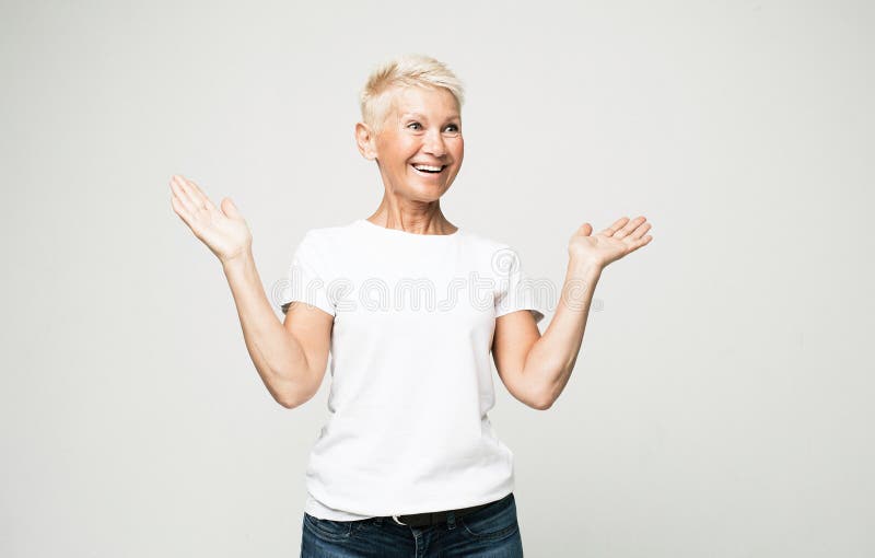 Femme âgée caucasienne avec cheveux courts isolés sur fond de studio gris se sentir surpris par l'accord ou la promotion. image libre de droits