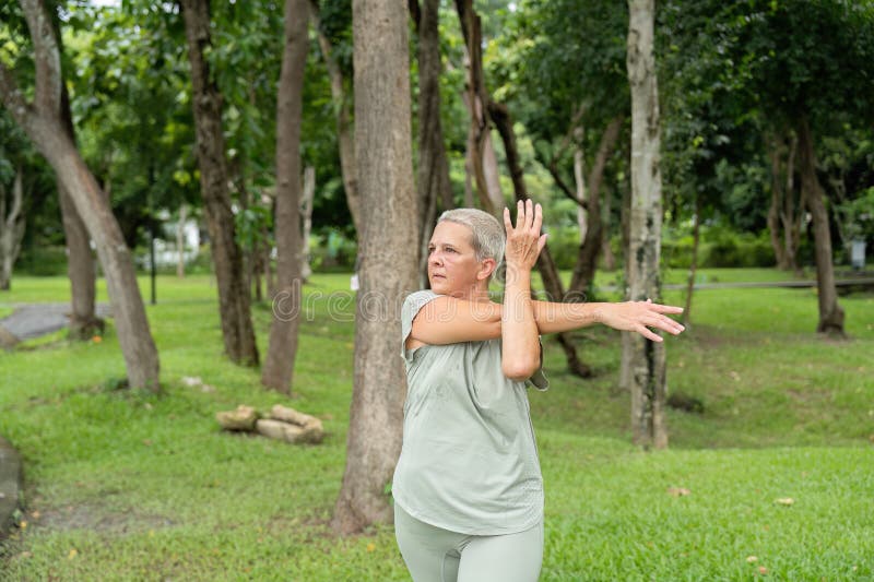 Femme âgée pratiquant le yoga et étirant les muscles dans un environnement de parc extérieur serein images libres de droits