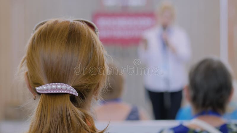 Femme écoutant le discours d'un conférencier méconnaissable à la conférence retour vue banque de vidéos
