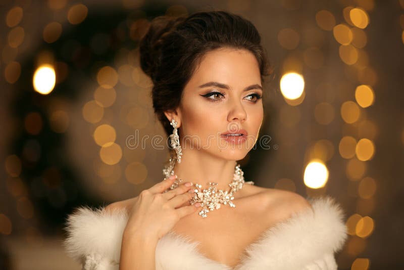 Femme élégante en fourrure blanche. Portrait de mode d'hiver de jolie mariée jeune avec des boucles d'oreille en diamant et l'ense photos libres de droits