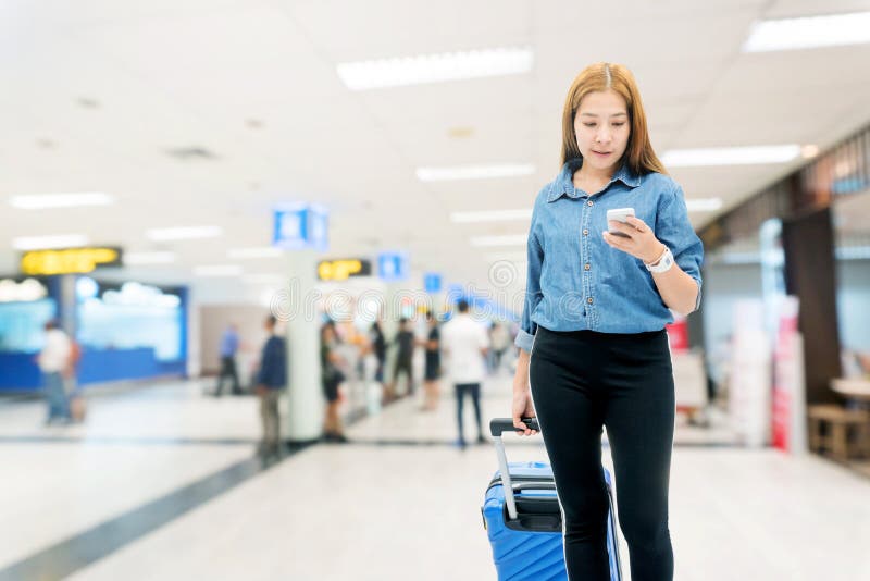 Femmes asiatiques de voyageur recherchant le vol dans le smartphone au concept de voyage de terminal d'aéroport image stock Femmes asiatiques de voyageur recherchant le vol dans le smartphone au concept de voyage de terminal d'aéroport image stock