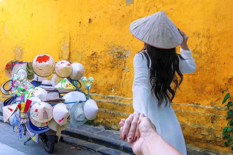 Femmes asiatiques en robes ao dai marchent main dans la main dans la ville antique de hoi an photos stock
