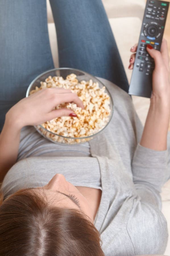 Femmes regardant la TV avec le maïs éclaté à la maison Vue supérieure photos libres de droits Femmes regardant la TV avec le maïs éclaté à la maison Vue supérieure photos libres de droits