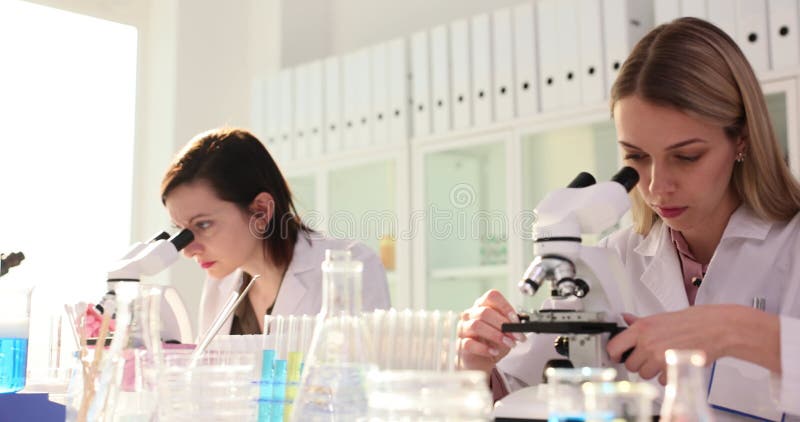 Femmes scientifiques à des tables avec microscopes et échantillons d'essai