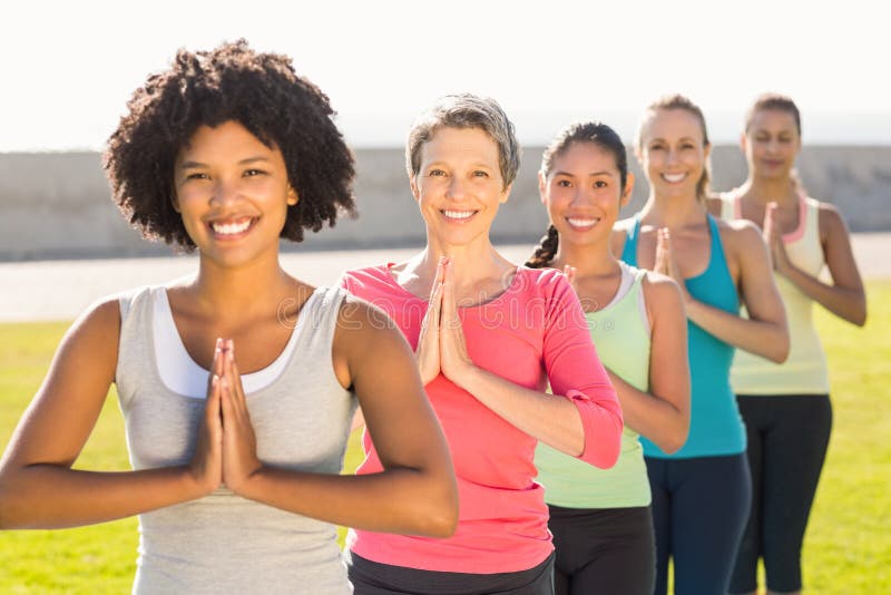 Femmes sportives de sourire faisant la position de prière dans la classe de yoga images stock Femmes sportives de sourire faisant la position de prière dans la classe de yoga images stock