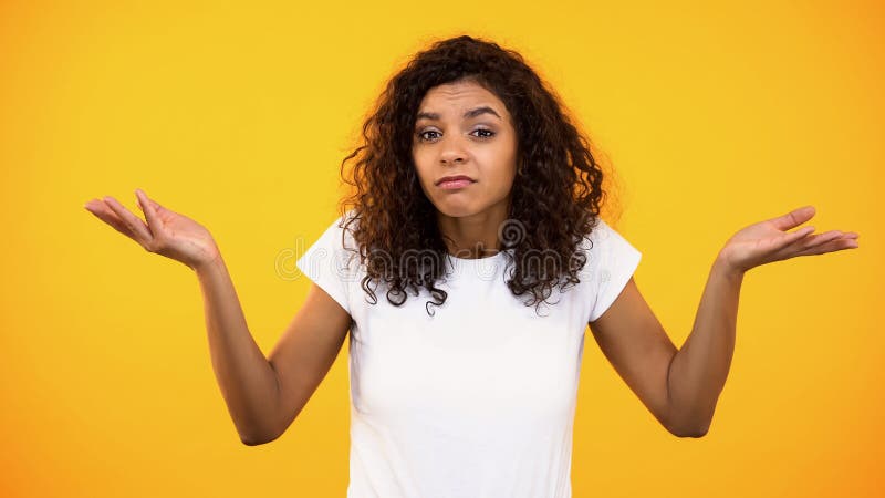Femmina afroamericana che non mostra gesto di idea, incerto della scelta, esitazione immagine stock Femmina afroamericana che non mostra gesto di idea, incerto della scelta, esitazione immagine stock