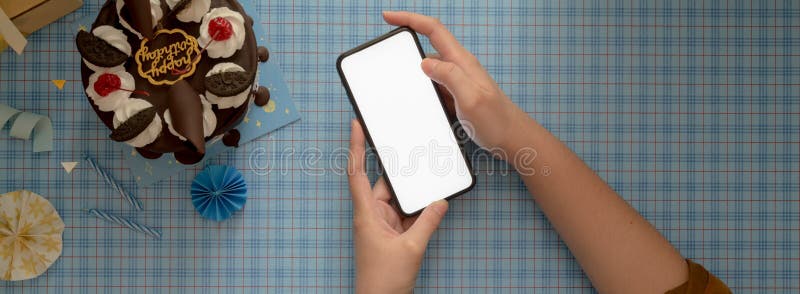 Femmina che usa uno smartphone per derubare sullo sfondo blu scott con torte e decorazioni immagine stock libera da diritti