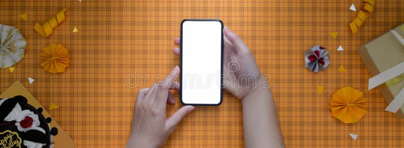 Femmina che utilizza smartphone bianco su sfondo giallo scott con scatola regalo per dolci e decorazioni fotografie stock libere da diritti
