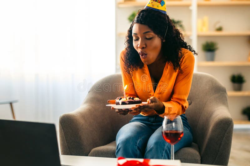 Femmina Nera Che Soffia Una Candela Su Torta Con Compleanno Online Al chiuso fotografia stock libera da diritti