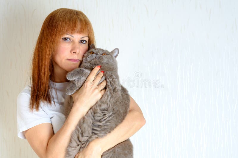 Femminile senior maturo dei peli biondi o rossi rilassandosi a casa gatto facente le fusa sveglio di tenuta e huging fotografie stock Femminile senior maturo dei peli biondi o rossi rilassandosi a casa gatto facente le fusa sveglio di tenuta e huging fotografie stock
