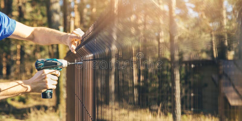 Fencing - worker installing metal wire mesh fence panel stock photos