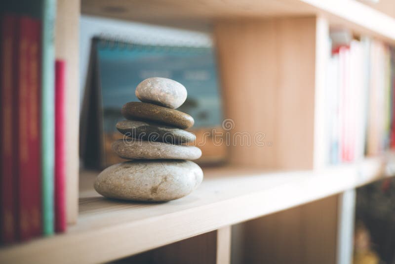 Feng Shui: Stone cairn in a book shelf in the living room, balance and relaxation. Sunlight