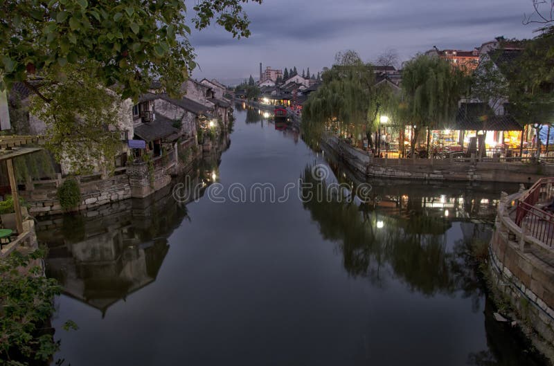 I tre area di ponte di Fengjing Città di Shanghai, illuminata di notte, che si riflettono nell'acqua calma.