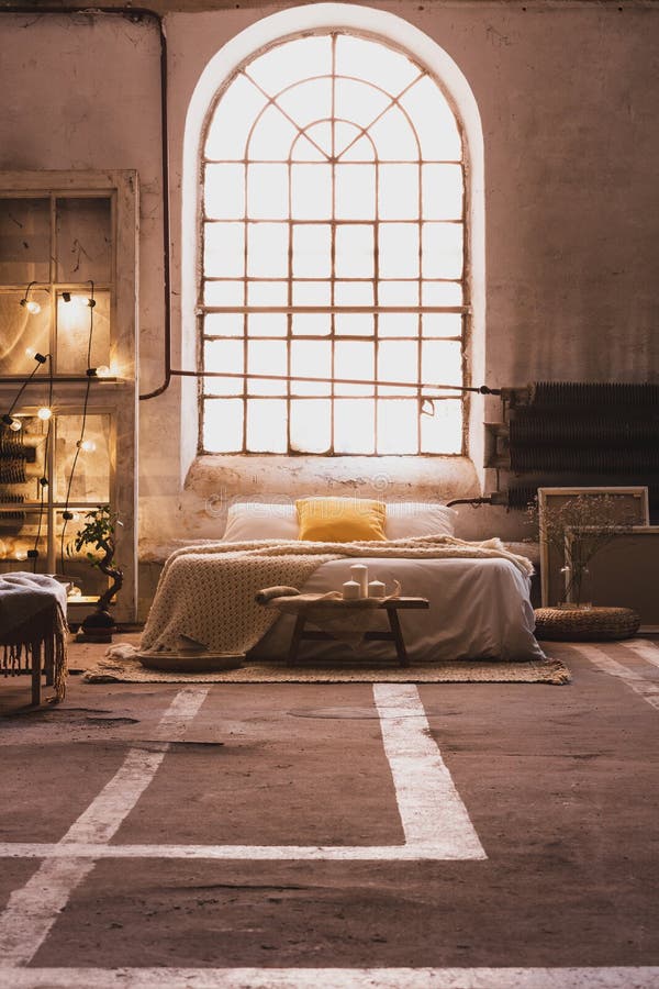 Fenêtre au-dessus de lit dans la chambre à coucher industrielle spacieuse photo libre de droits Fenêtre au-dessus de lit dans la chambre à coucher industrielle spacieuse photo libre de droits