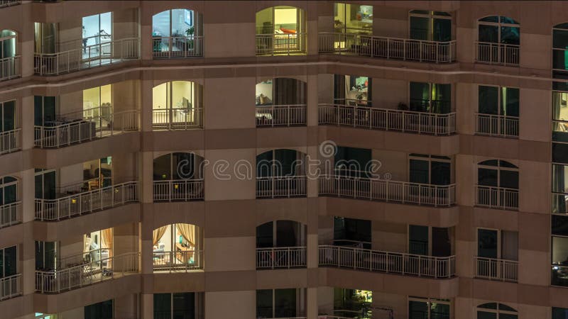 Fenêtres dans le bâtiment à plusieurs étages avec la lumière à l'intérieur et les gens en mouvement dans le timelapse d'apparteme banque de vidéos