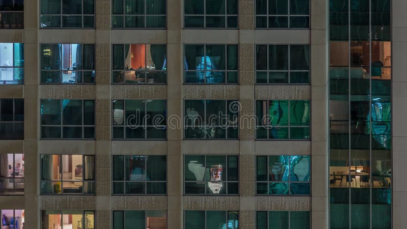 Fenêtres dans le bâtiment à plusieurs étages avec la lumière à l'intérieur et les gens en mouvement dans le timelapse d'apparteme banque de vidéos