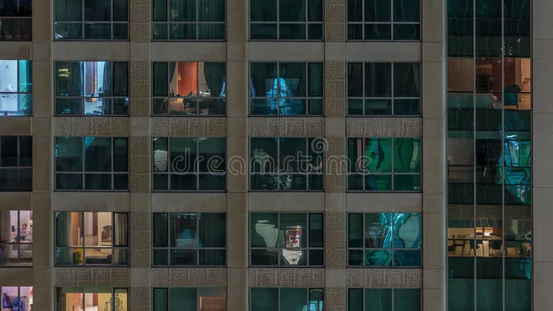 Fenêtres dans le bâtiment à plusieurs étages avec la lumière à l'intérieur et les gens en mouvement dans le timelapse d'apparteme banque de vidéos