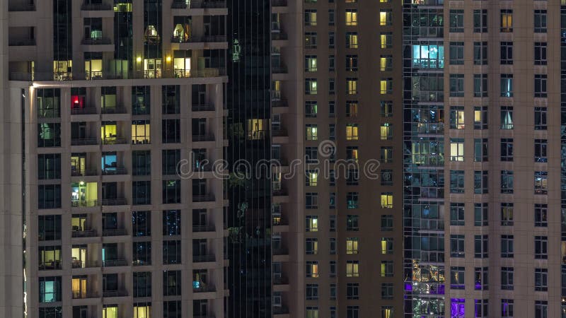 Fenêtres de l'immeuble de plusieurs étages avec éclairage à l'intérieur et déplacement des personnes dans les appartements timela banque de vidéos