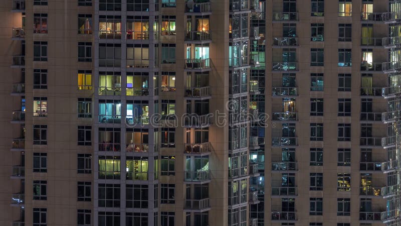Fenêtres de l'immeuble de plusieurs étages avec éclairage à l'intérieur et déplacement des personnes dans les appartements timela banque de vidéos