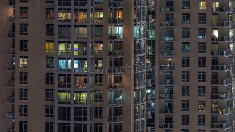 Fenêtres de l'immeuble de plusieurs étages avec éclairage à l'intérieur et déplacement des personnes dans les appartements timela banque de vidéos