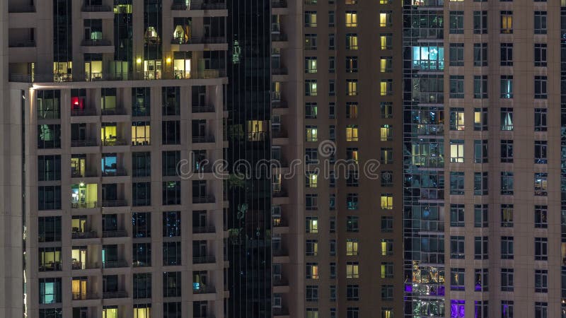 Fenêtres de l'immeuble de plusieurs étages avec éclairage à l'intérieur et déplacement des personnes dans les appartements timela clips vidéos