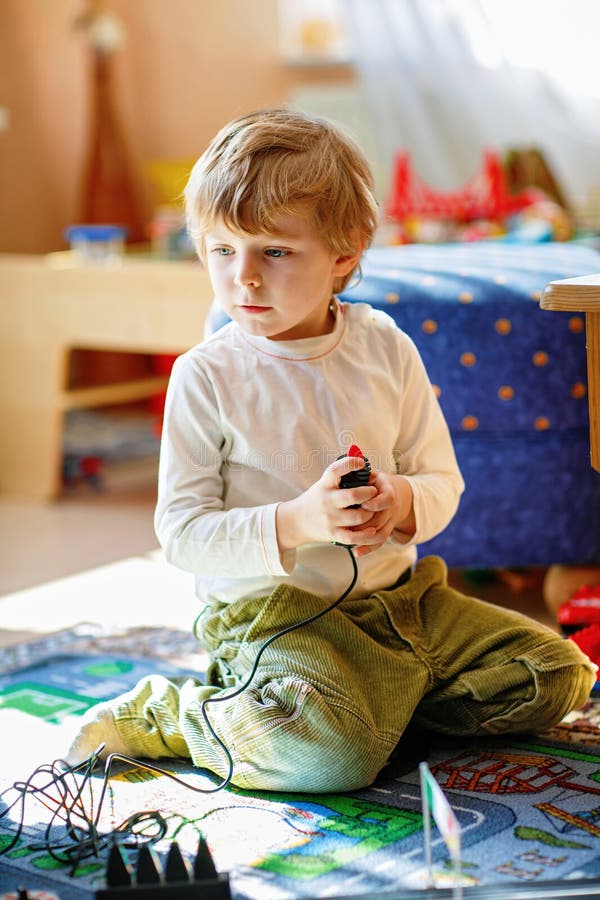 Fericit drăguț băiat preșcolar joc cu mașini de curse pe pistă de curse în interior cu mașini. Excitat copil având distracție cu j royalty free stock photography
