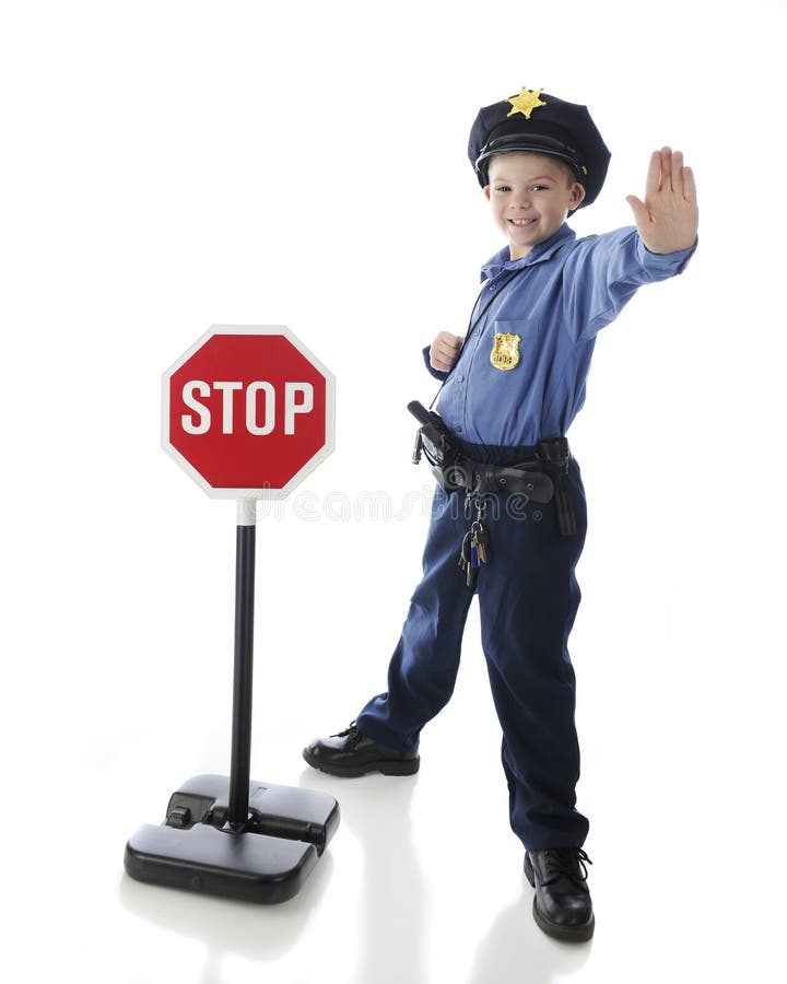 An adorable elementary boy gesturing to stop while in his police uniform and standing by a stop sign. On a white background. An adorable elementary boy gesturing to stop while in his police uniform and standing by a stop sign. On a white background.