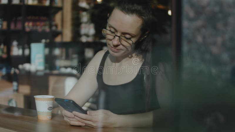 Fermer le téléphone cellulaire d'une femme. regarder la vidéo sur téléphone portable pendant la pause café. vue de l'extérieur clips vidéos