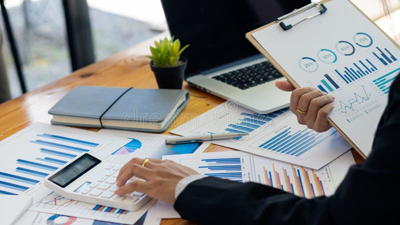 Fermer les gens d'affaires à l'aide d'une calculatrice pour écrire des notes avec des calculs analyse graphique sur les concepts de comptabilité financière.