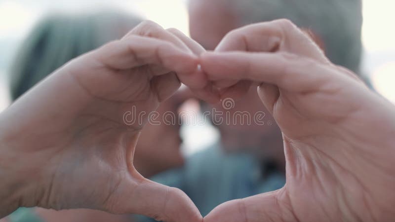Fermer portrait heureux sincère moyen-âge âgé retraité couple faisant un geste de coeur avec des doigts montrant l'amour ou clips vidéos