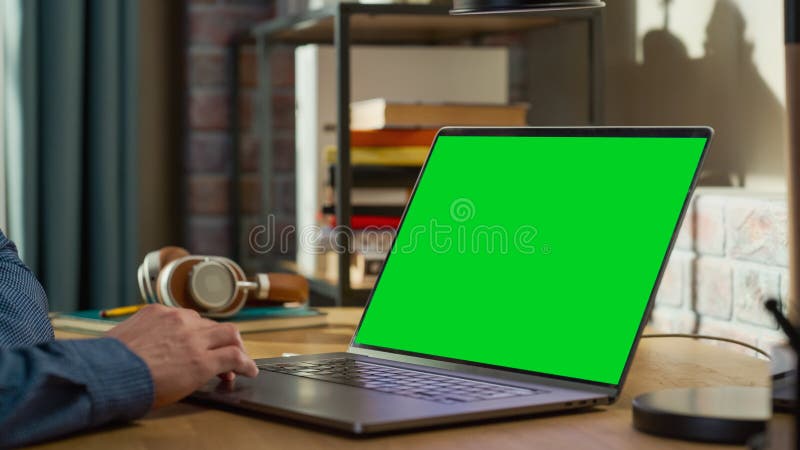 Close Up on Male Hands Working from Home on Laptop Computer with Green Screen Display, Person Using Trackpad. Student Making Homework, Studying for School Exams. Young Adult Checking Social Media. Close Up on Male Hands Working from Home on Laptop Computer with Green Screen Display, Person Using Trackpad. Student Making Homework, Studying for School Exams. Young Adult Checking Social Media.