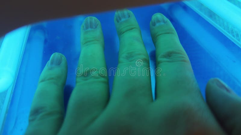 Fermer vue main dans le sèche-ongles led. lampe uv avec lumière bleue. processus de manucure. palme main macro. pixel du grain de banque de vidéos