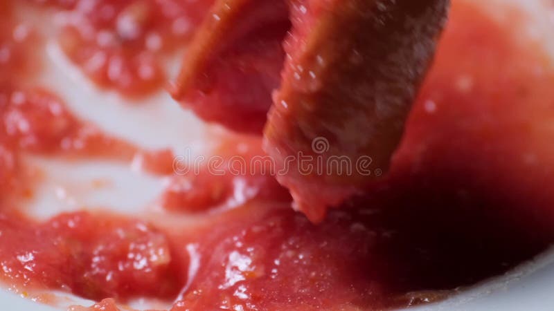 Fermeture d'un morceau de saucisse trempé dans une sauce rouge