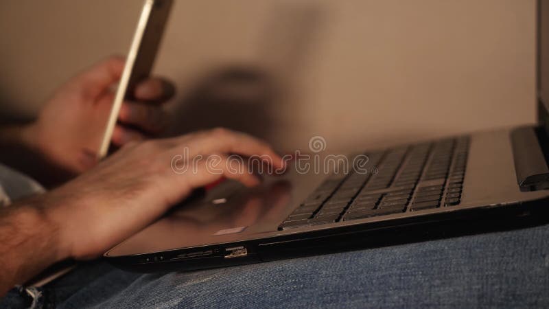 Fermeture d'un moyen dactylographiant à la main sur un ordinateur portable qui se trouve sur ses genoux. dans l'autre main est un banque de vidéos