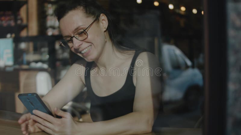 Fermeture d'une femme tenant le téléphone cellulaire dans un caffe. parler à un ami sur un téléphone portable pendant une pause ca clips vidéos